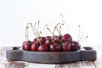 A handful of cherries on a wooden board on a white background.