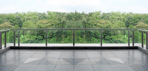 Panoramic view of a green forest canopy from a modern glass balcony.