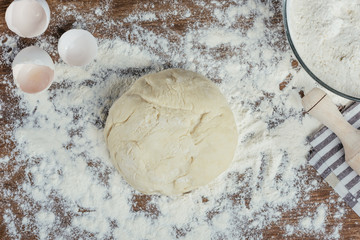 Top view of fresh unbaked dough in flour on wooden table top