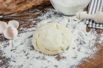 Close-up view of fresh unbaked dough in flour on wooden table top
