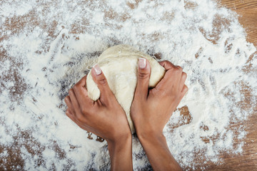 Cropped shot of hands kneading dough on wooden table top © LIGHTFIELD STUDIOS