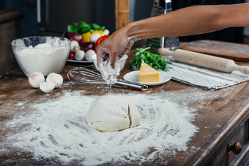 Cropped shot of woman preparing pizza dough in kitchen