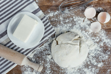 Top view of unbaked dough with ingredients and rolling pin on table top
