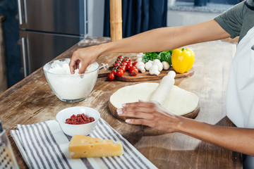 Cropped shot of person rolling dough while cooking pizza