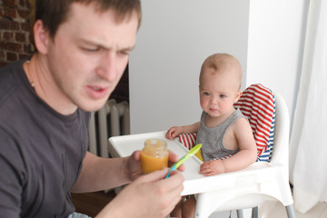 Obraz na płótnie Canvas Father feeding infant son