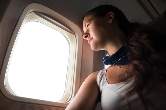 Young woman looking through window in airplane