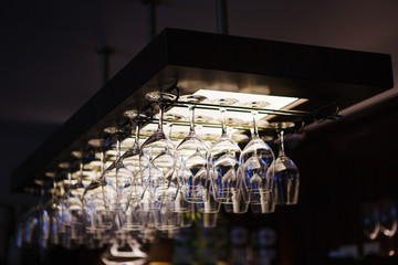 Empty wine glasses hanging upsidedown in bar interior.