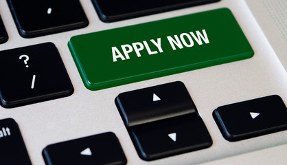 Computer notebook keyboard with Apply Now key, silver laptop with black keyboards, finger want to press the key