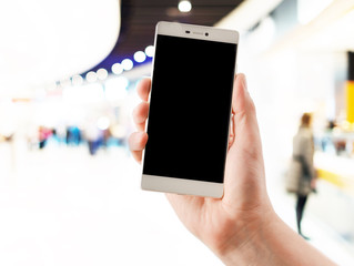 Hands holding smart phones on blurred supermarket  background