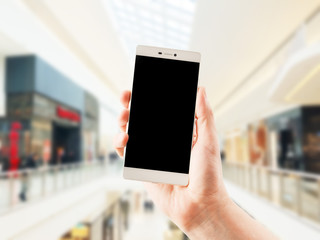 Hands holding smart phones on blurred supermarket  background