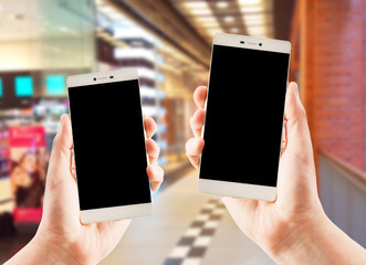 Hands holding smart phones on blurred supermarket  background