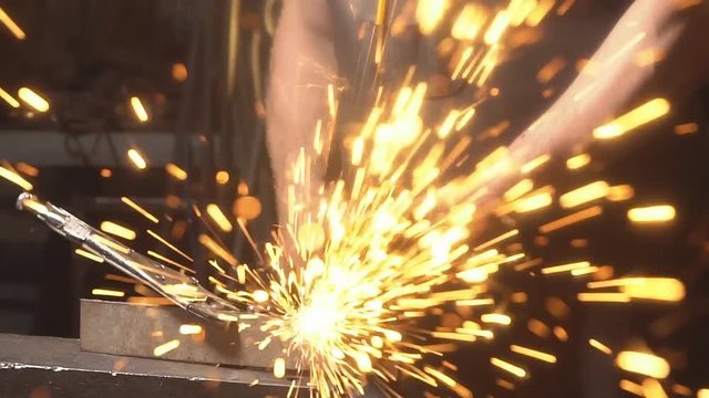Sparks flying at the camera. Man working angular grinding machine. Slow motion