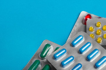 Colored pills, tablets and capsules on a blue background. Medicine and health.