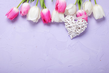 Border from  tulips flowers and decorative heart  on violet  textured background.