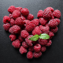 raspberries heart on black background