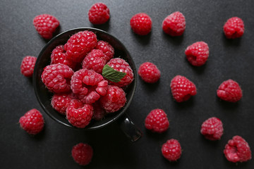 closeup of fresh raspberries in a cup on black background