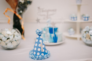 Праздничный бумажный колпак на фоне стола с тортом по случаю дня рождения