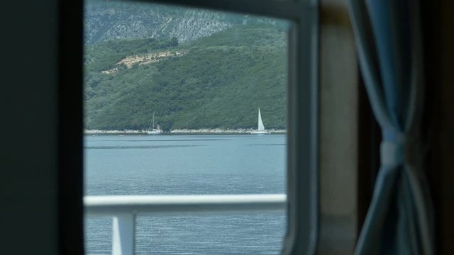 Inside cabin view of seascape and islands by a travelling passengers ship.