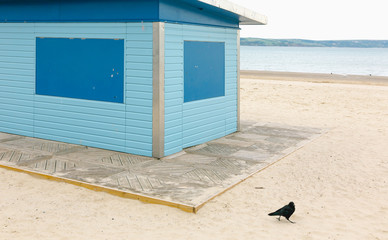 Blue old beach shop closed in morning hours on Weymouth beach by calm sea