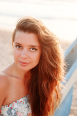 Close-up portrait of a girl with long hair at sunset, she smiles