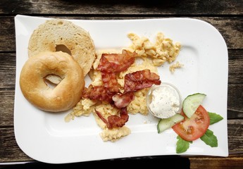 Breakfast with scrambled eggs and bacon Outdoors on old wood table 