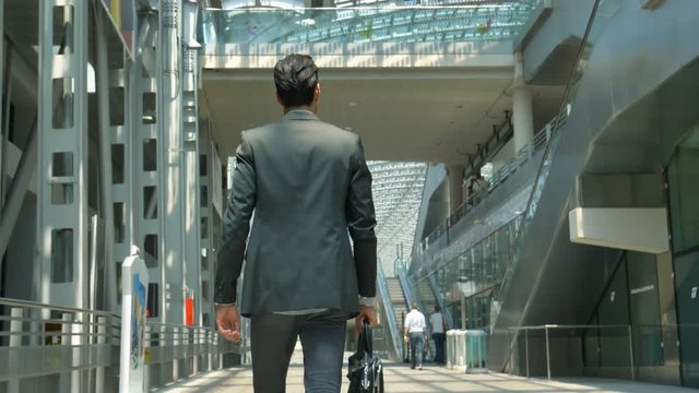A young handsome businessman (student) in a suit, comes with a briefcase, at the station, at the airport. Concept: a new business, traveling the world, communication, contacts, a new deal, success.