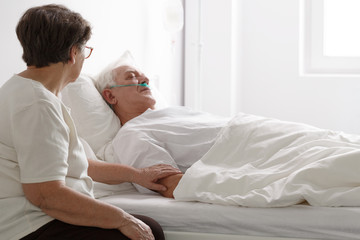 Man in a coma and his wife sitting next to him