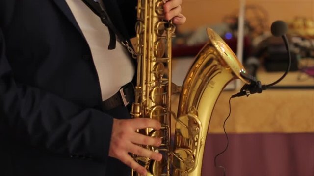 Saxophonist in a tuxedo plays music on sax. Musician plays the saxophone performance at a concert. Jazz night
