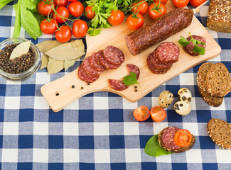 Sliced salami with cherry tomatoes and spices on table