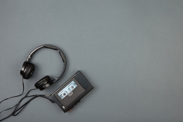 Retro cassette player with headphones on grey background