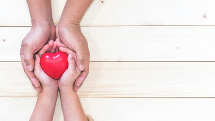 Parent supporting child's hands with red heart for I love you dad and Father's Day holiday...