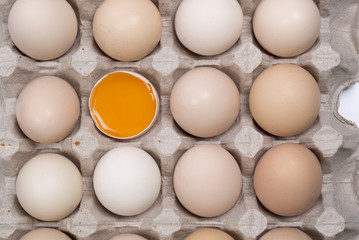 Box filled with eggs, with one broken egg, high angle view.