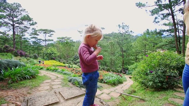 Mother Gives Little Girl Ice Cream Tube on Stone Path in Park