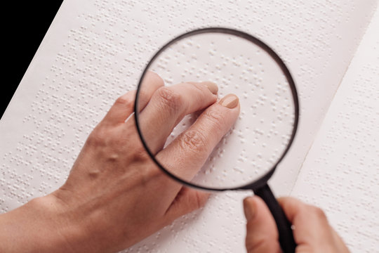 Finger read braille alphabet in white paper.