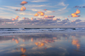 clouds reflections on beach at the sunset