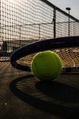 Tennis ball and racket on hard court under sun light