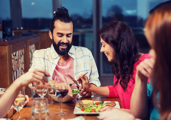 friends eating and tasting food at restaurant