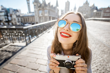 Portrait of a young woman tourist with photo camera traveling in the old town of Gent city during the sunrise in Belgium
