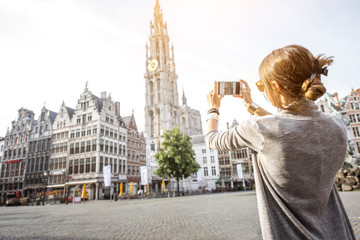 Young woman tourist photographing with phone famous cathedral standing on the Great Market square...