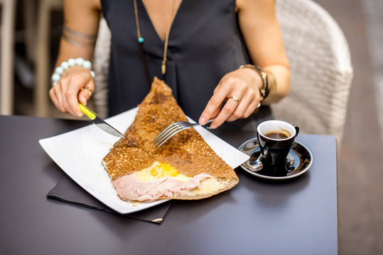 Traditional french pancake called galette cooked with buckweat and stuffed with cheese egg and ham on the restaurant table with coffee