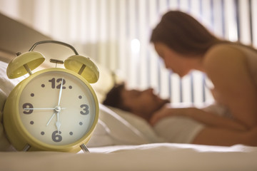 The clock on the background of the couple in the bed