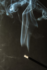 Burning incense sticks with smoke on dark background
