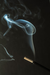Burning incense sticks with smoke on dark background