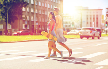 teenage couple with skateboards on city street