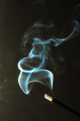 Burning incense sticks with smoke on dark background