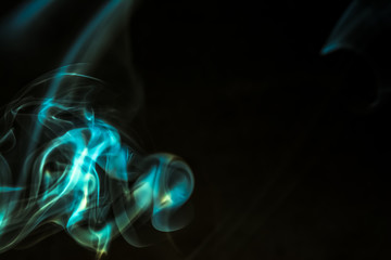 Smoke from burning incense sticks on dark background