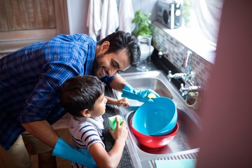 Father and son cleaning utensils at home
