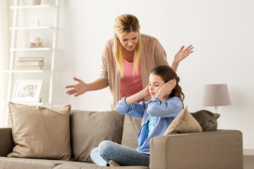 girl closing ears to not hear angry mother at home