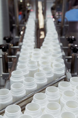 white plastic bottle on the production line of the conveyor at filling machine in the factory. selective focus.