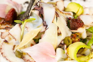 Salad from avocado with octopus and parmesan cheese.